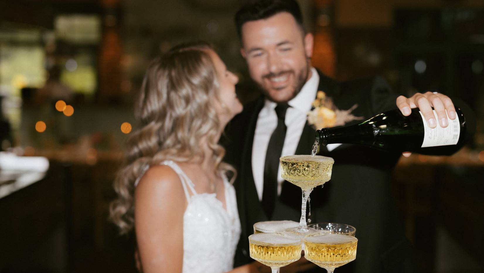 Braut und Bräutigam gießen Sekt ein
