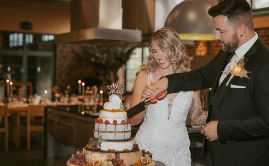 Hochzeitspaar schneidet Kuchen an in der Scheck-in Kochfabrik